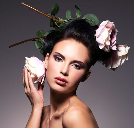 性感美丽的年轻女子的肖像与鲜花在头发的姿势成人女人女性