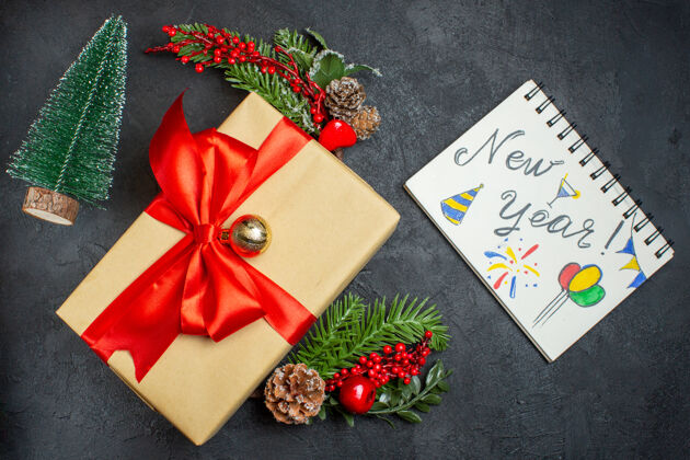 容器圣诞气氛与蝴蝶结形彩带和杉木枝装饰配件xsmas袜子笔记本与新年图纸上的一个黑暗的背景美丽的礼物树枝笔记本风车