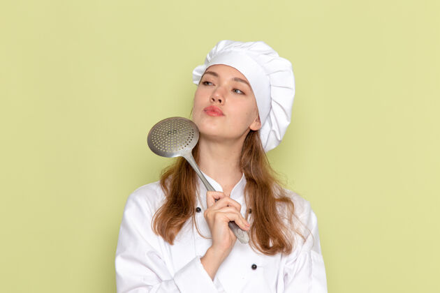 银身穿白色厨师服的女厨师手持大银勺 在绿墙上思考肖像烹饪穿