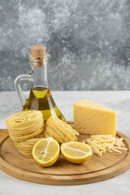 意大利面白桌上放着意大利面 油 柠檬奶酪的木板瓶子一半奶酪