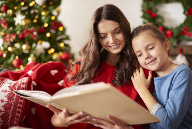 舒适妈妈和女儿在圣诞节读书圣诞孩子微笑