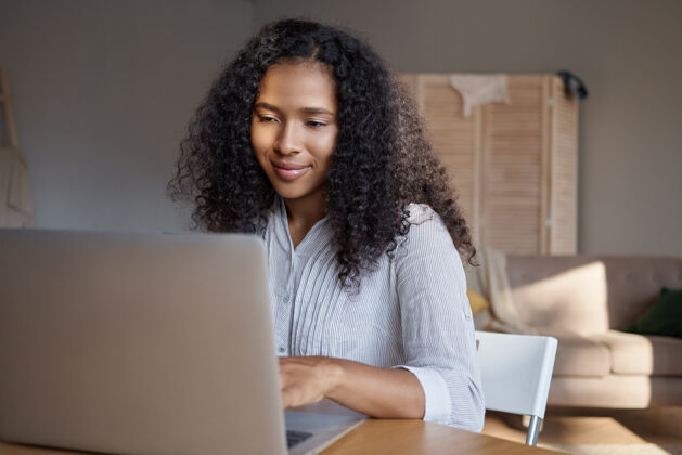 现代时尚的年轻黑人女性卷发使用笔记本电脑进行远程工作可爱的非洲女孩在互联网上寻找信息 在家享受electronicgadget上的高速无线连接工作笔记本非洲