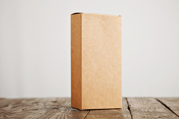 包装工艺纸板包装盒垂直呈现在强调拉丝木桌上 隔离在白色背景上盒子纸箱旧的