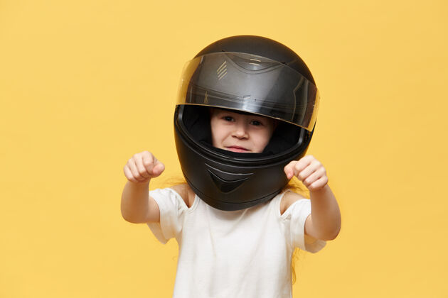 摩托车交通 极限 赛车运动和活动的概念危险的小女孩骑在黑色保护摩托车头盔保持双手在她面前 好像驾驶摩托车的画像头盔孩子设备