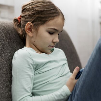 防护小女孩在室内玩智能手机冠状病毒家庭教育病毒