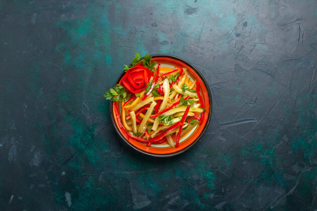 不同的顶视图切碎的甜椒不同颜色的蔬菜沙拉在深蓝色背景的盘子里胡椒盘子里面