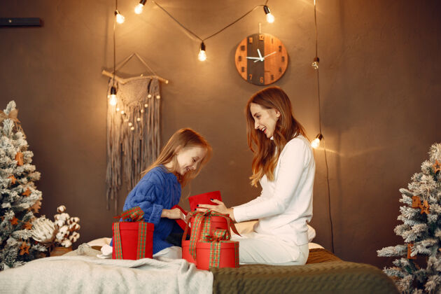 人人们在为圣诞节做准备母亲在和女儿玩耍一家人在节日的房间里休息孩子穿着蓝色毛衣女人女儿休闲