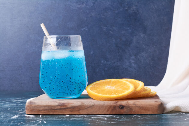 生物橘子片配一杯饮料放在蓝色上食物美味酒吧