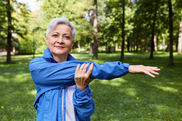 老年人夏季图片健康活跃的退休妇女微笑 伸展手臂肌肉后 户外跑步训练 在森林中摆姿势健康 幸福 年龄 人 运动和活动的概念女人老年人身体