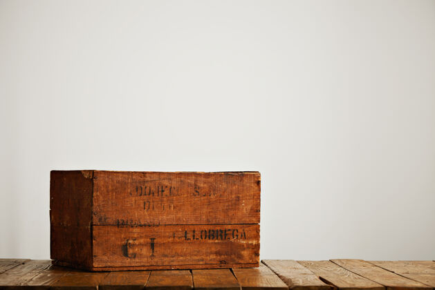 墙壁在一间白墙工作室的木桌上放着一个棕色破旧的乡村盒子 上面有黑色的字母货物地方运输