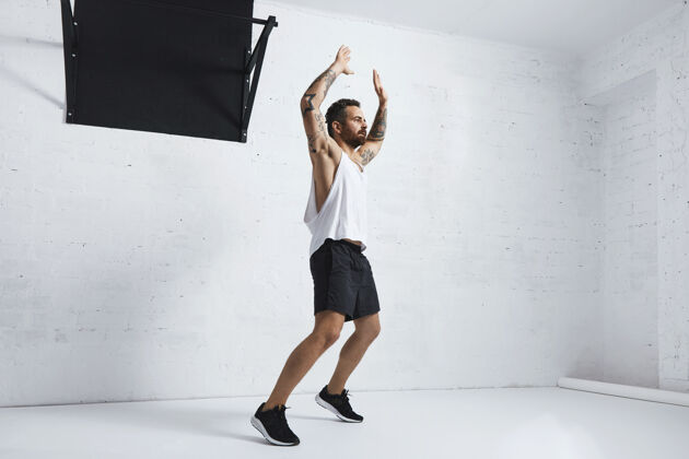 锻炼纹身和肌肉运动员做跳跃杰克隔离在白色砖墙旁边的黑色拉杆 看右边体操运动员身体年轻