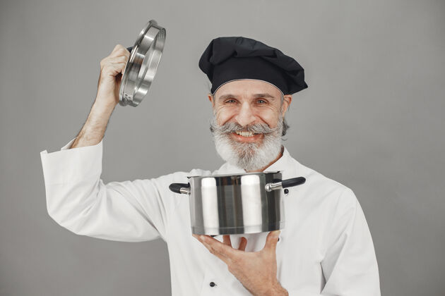 烹饪高级男子与金属锅厨师在一个黑色的帽子专业的方法来处理业务厨房人工人