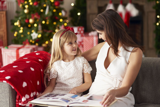 圣诞节一位家长给女儿读书女孩微笑客厅