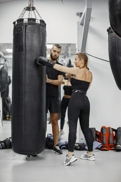 器械女子拳击健身房的初学者穿黑色运动服的女士有教练的女士手套运动武术
