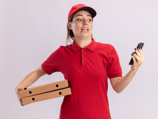 制服焦急的年轻漂亮的女送货员穿着制服拿着比萨饼盒 看着电话焦虑女人表情