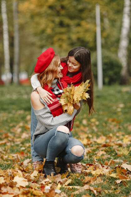 乐趣时髦的母亲带着女儿黄色的秋天戴着红领巾的女人自然父母孩子