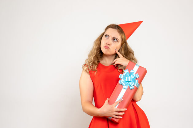 庆祝正面图身着红色连衣裙的年轻女性用礼物庆祝圣诞节颜色美丽女士