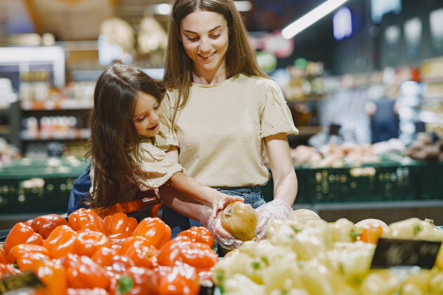 黑发一家人在超市里一个穿着棕色t恤的女人人们选择蔬菜妈妈带着女儿购买女人一起