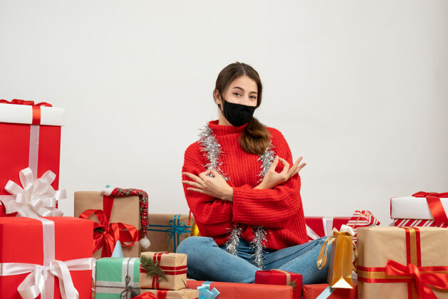 肖像穿着红色毛衣 戴着黑色面具的年轻女孩 围坐在白色的礼物旁边 做着一个好牌子毛衣圣诞节坐着