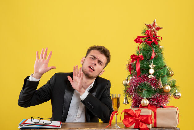 商人正面图：坐在黄色工作台后面的男工人圣诞节男情绪