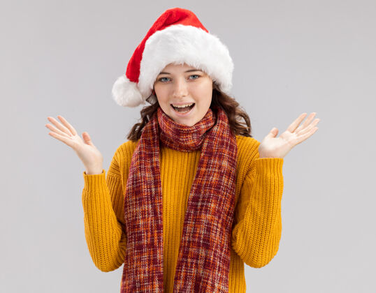 周围快乐的年轻斯拉夫女孩 戴着圣诞帽 脖子上围着围巾 双手张开 在白色背景上 有复制空间打开女孩圣诞快乐