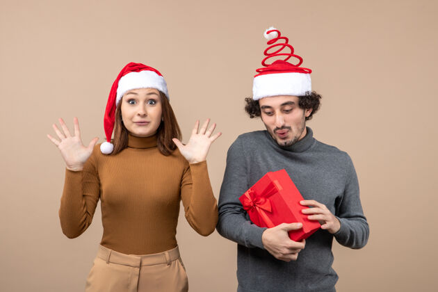 男人新年气氛喜庆的概念与搞笑快乐可爱的夫妇戴着灰色股票上的红色圣诞老人帽的形象头盔心情帽子