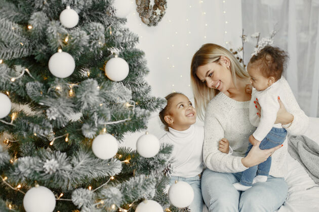 闪亮人们在为圣诞节做准备母亲在和女儿们玩耍一家人在节日的房间里休息孩子穿着毛衣家毛衣室内