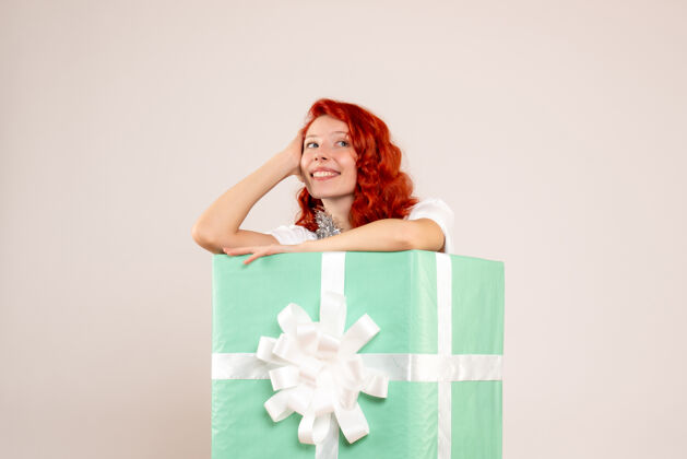 礼物隐藏在白墙上的年轻女子的正面视图圣诞快乐十二月人