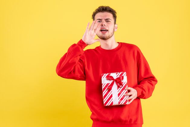 某人正面图：穿着红色衬衫的年轻男性 带着圣诞礼物 正在呼叫某人衬衫颜色情感