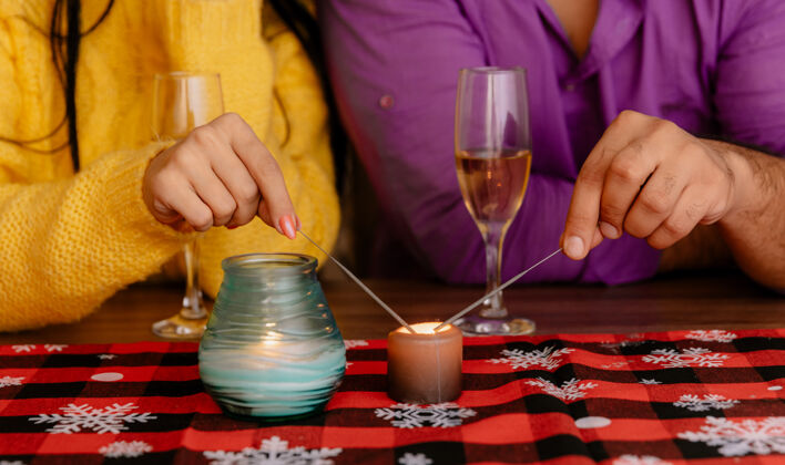 摆设一对夫妇的手放在桌子边放着香槟的火花点燃的剪影照片不规则桌子香槟