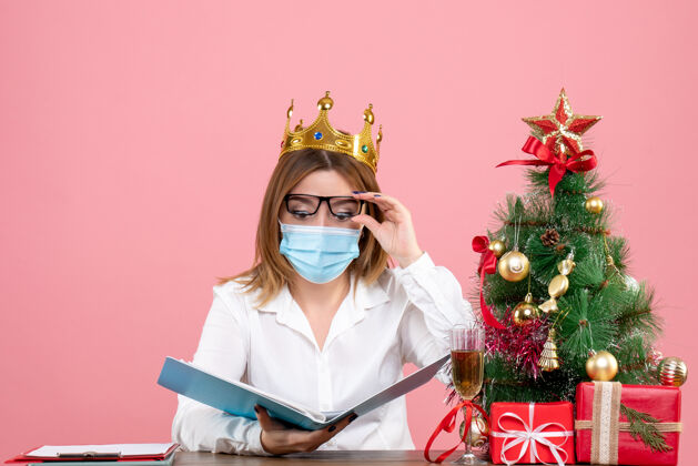 专业女工戴着无菌口罩坐着的正面图 粉红色的文件面具脸圣诞节
