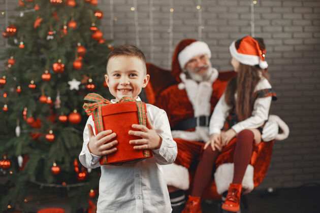 年轻圣诞节 孩子们和礼物圣诞老人给孩子们带来礼物快乐的孩子们带着礼物拥抱圣诞老人孩子三惊喜