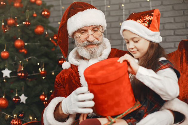 圣人圣诞节 孩子和礼物圣诞老人给孩子带来礼物快乐的小女孩拥抱圣诞老人家肖像男人