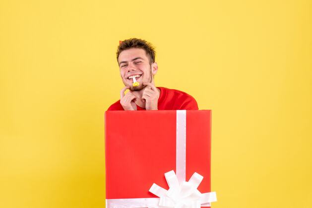 坐着正面图穿红衬衫的年轻男子坐在礼品盒内红色微笑盒子