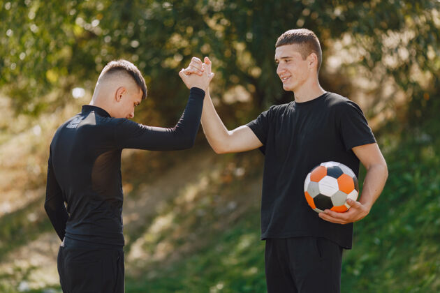 朋友男子在公园玩足球迷你足球锦标赛穿黑色运动套装的家伙足球户外学校