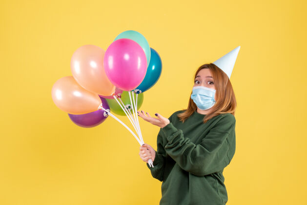 女人正面图戴面具的年轻女性手持五颜六色的气球情感庆祝生日
