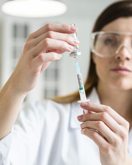 女性女科学家的前视图 戴着安全眼镜 手里拿着装有疫苗的注射器实验安全科学
