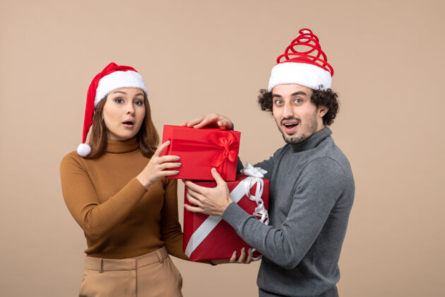 可爱的情侣新年气氛喜庆概念搞笑快乐可爱情侣戴红色圣诞老人帽礼物献礼仪式上灰帽子帽子情侣