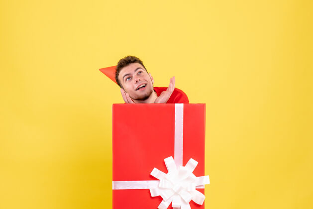 年正面图：礼品盒内穿红色衬衫的年轻男性圣诞节购物纸