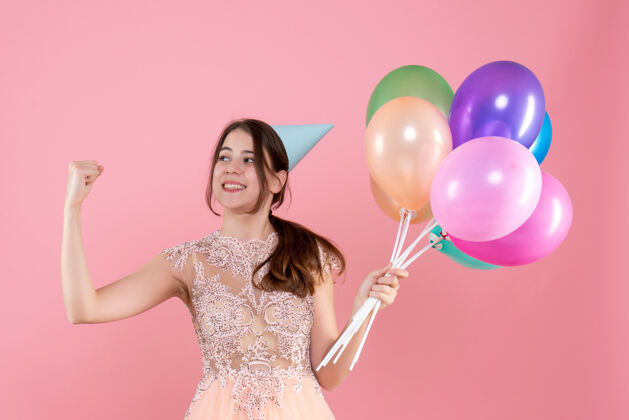 肖像快乐的派对女孩 戴着派对帽 手里拿着气球 展示着粉色的肌肉可爱快乐派对女孩生日