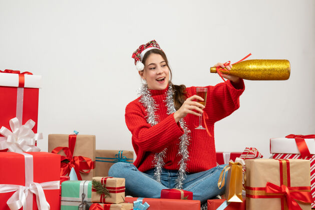 女孩戴着圣诞帽 倒香槟的快乐派对女孩围坐在白色的礼物旁礼物卖家快乐