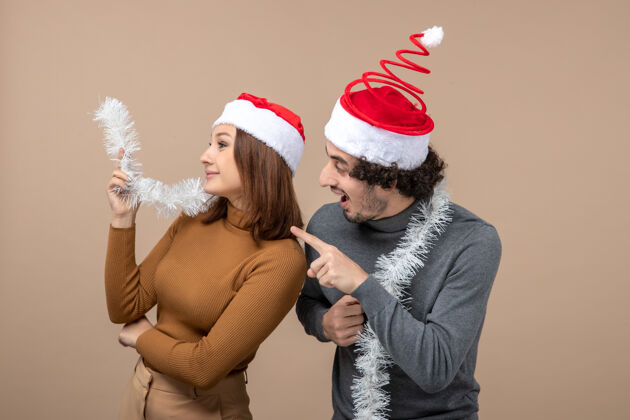 服装新年心情喜庆的概念与兴奋酷满意可爱的情侣戴着红色圣诞老人帽灰色圣诞老人圣诞老人兴奋
