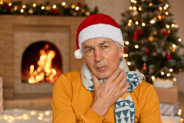 困倦穿着橙色毛衣 围巾和圣诞帽的病人喉咙痛家伙健病