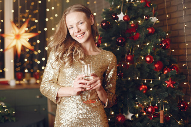 聚会圣诞树旁的优雅女士家里拿着香槟的女士女孩时尚节日