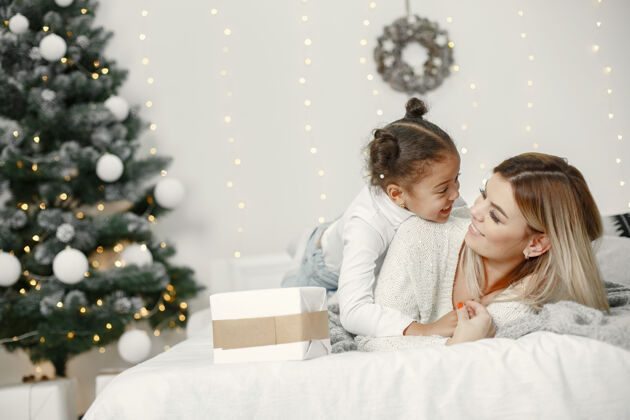 小人们在为圣诞节做准备母亲在和女儿玩耍一家人在节日的房间里休息孩子穿着毛衣女儿花环礼物