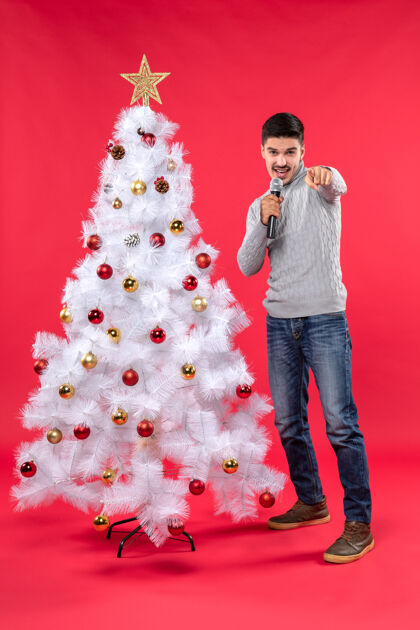 成人新年气氛积极的家伙穿着牛仔裤站在装饰圣诞树附近圣诞树欢快圣诞节