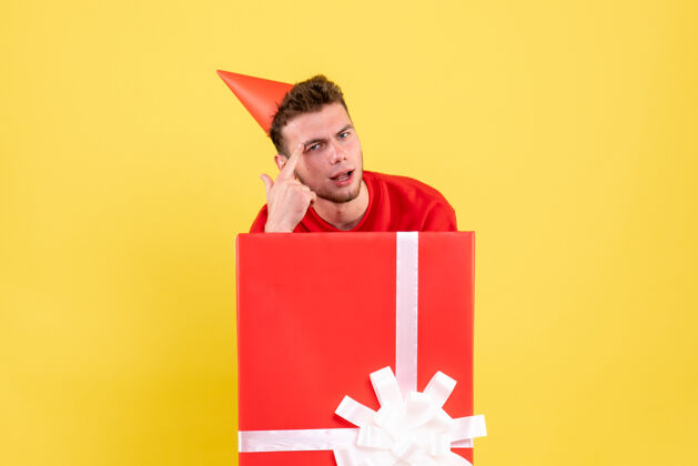 年轻正面图穿红衬衫的年轻男子坐在礼品盒内年份里面丝带