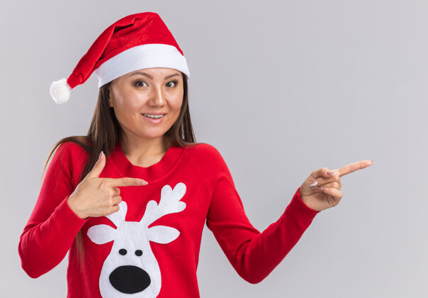 女孩笑容可掬的亚洲女孩戴着圣诞帽 边上有毛衣点 白色背景上有复制空间边帽子点