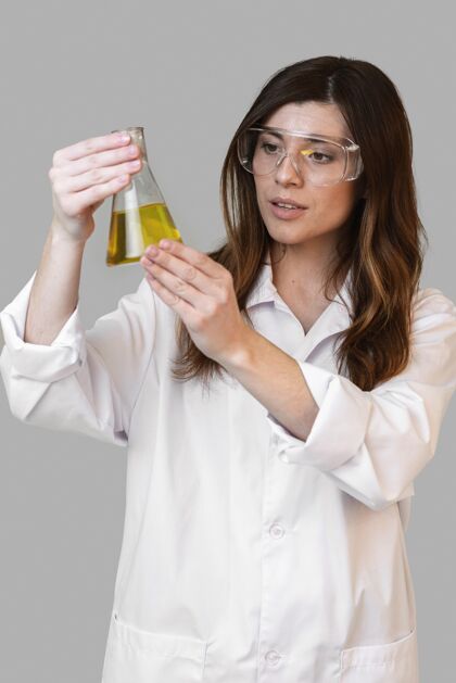 垂直女药剂师戴着安全眼镜拿着试管的前视图创新者研究炼金术