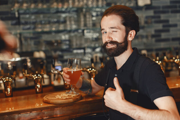 喝酒一个留着胡子的男人站在吧台旁 喝着酒杯里的酒休息表情现代